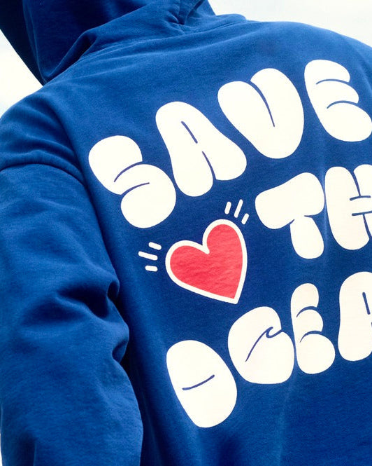 Blue hoodie with 'Save the Ocean' text and heart graphic on a blurred natural background
