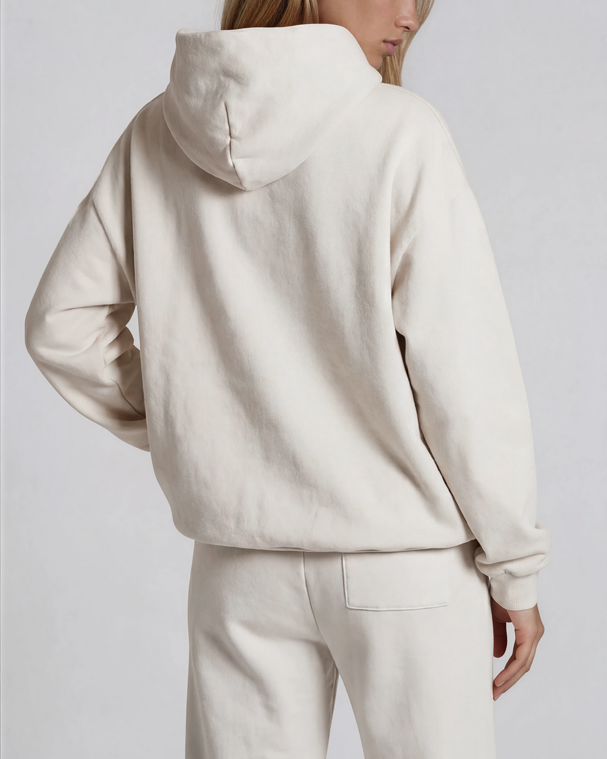 Person wearing a beige hoodie and pants on a plain background