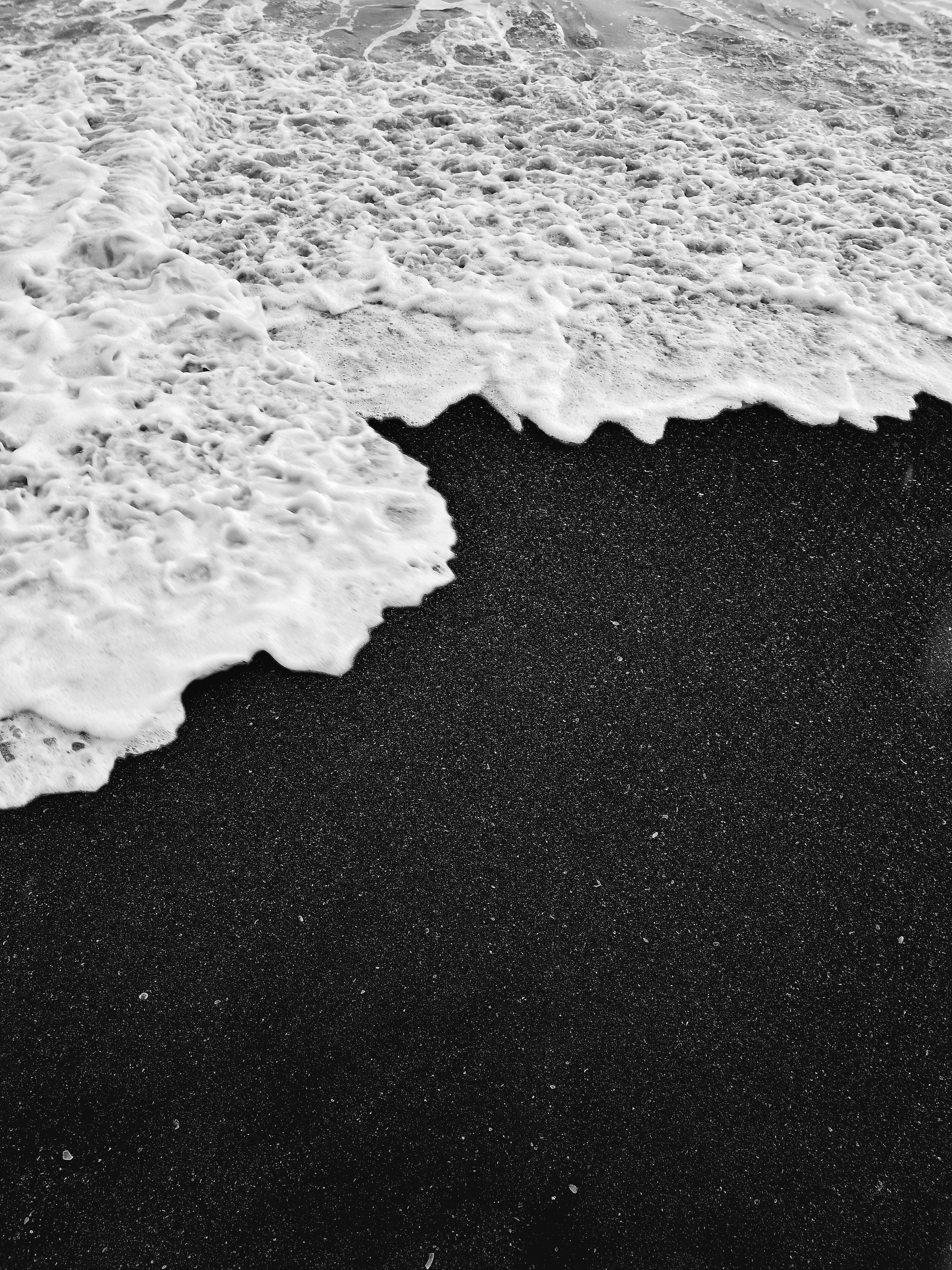 Close-up of white foam on a black sand beach